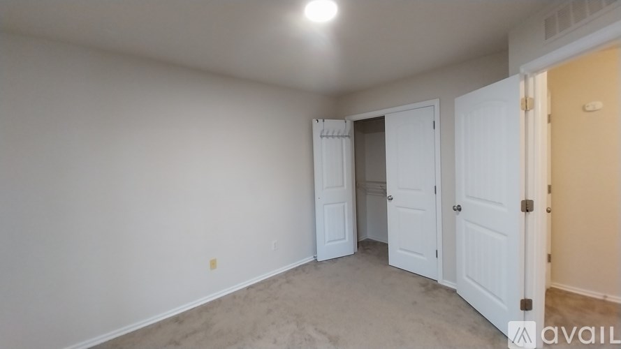 A room with a white door and a beige carpet.