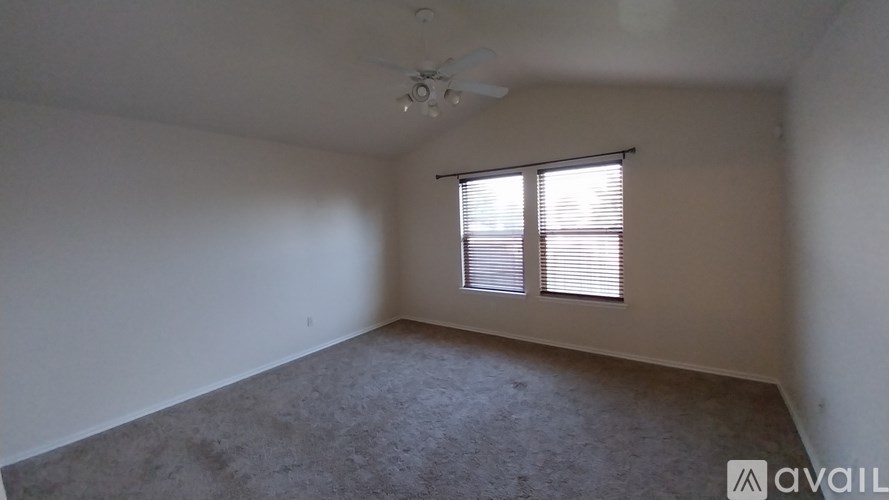 A room with a ceiling fan and a window with blinds.