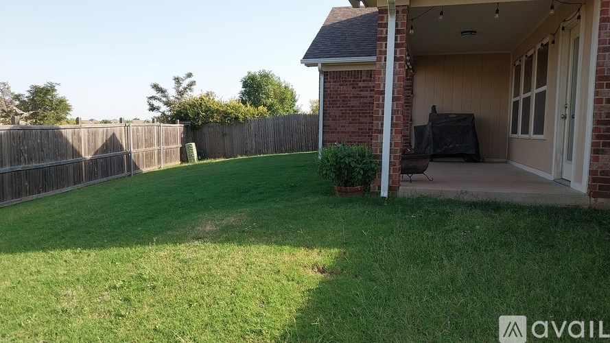 A backyard with a wooden fence and a covered patio area.