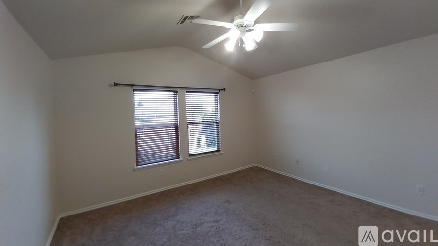 A room with a ceiling fan and a window with blinds.