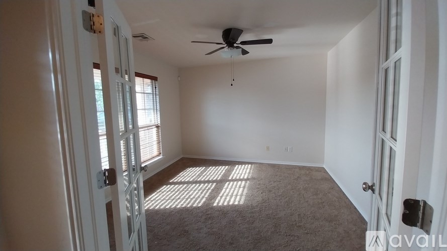 A room with a ceiling fan and carpeted floor.