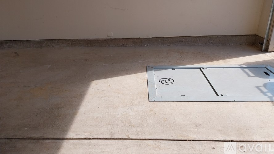 A metal ventilation grate is on a concrete floor.