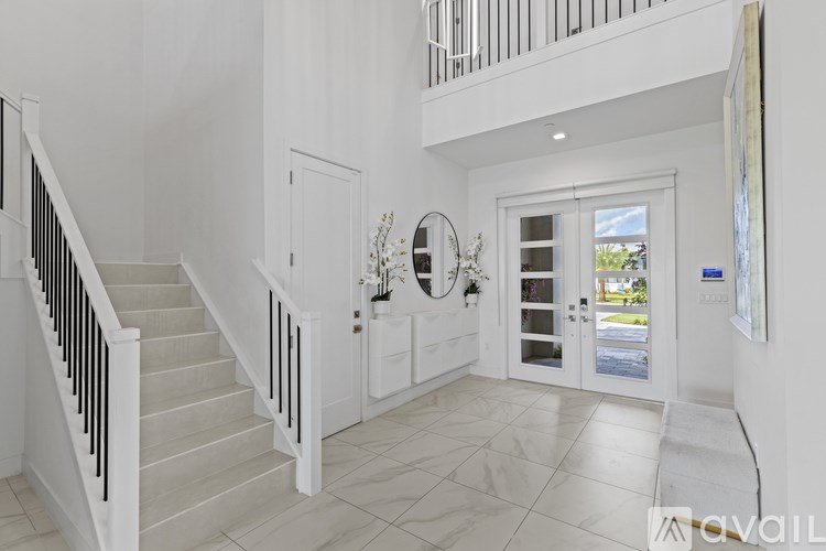 A spacious, well-lit foyer with a staircase and a view of the outdoors.