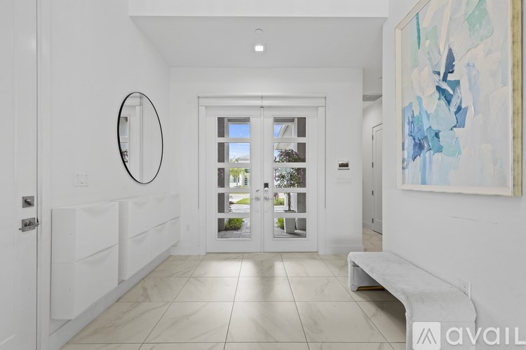 A hallway with a white bench, a painting on the wall, and a mirror on the wall.