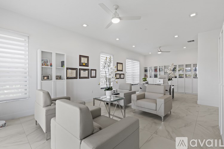 A living room with a white ceiling fan and white walls.