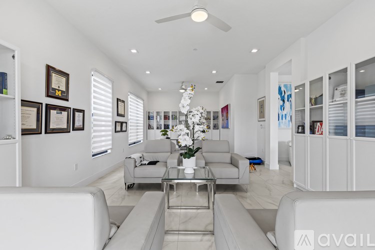 A modern living room with a glass coffee table and white furniture.