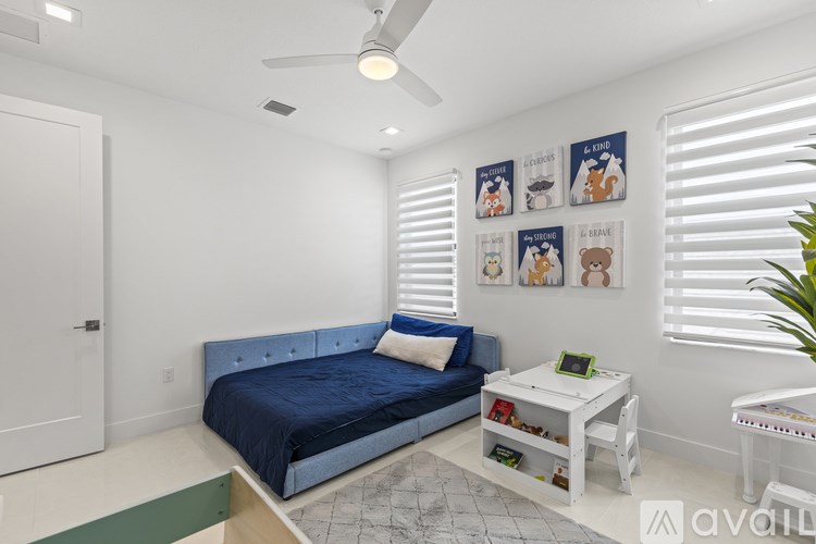 A bedroom with a blue bed and a white table.