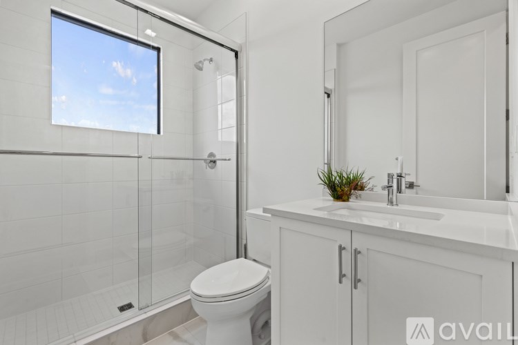 A white bathroom with a toilet, sink, and a window.