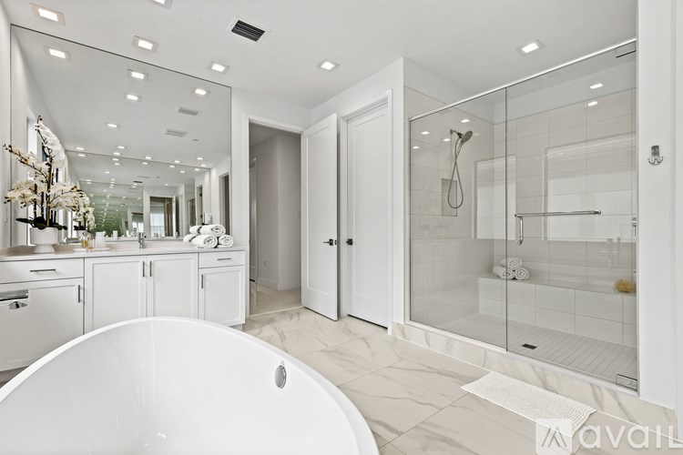 A white bathroom with a tub, sink, and shower.
