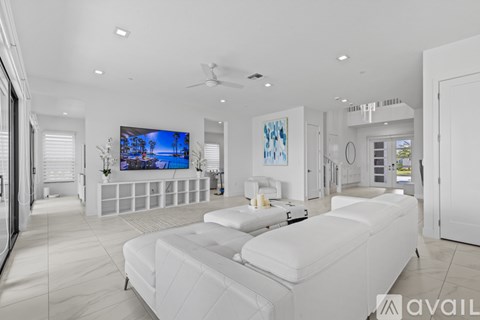 A modern living room with a white sofa and a flat screen TV mounted on the wall.