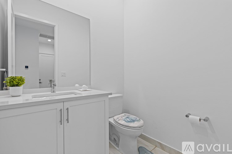 A white bathroom with a toilet, sink, and mirror.