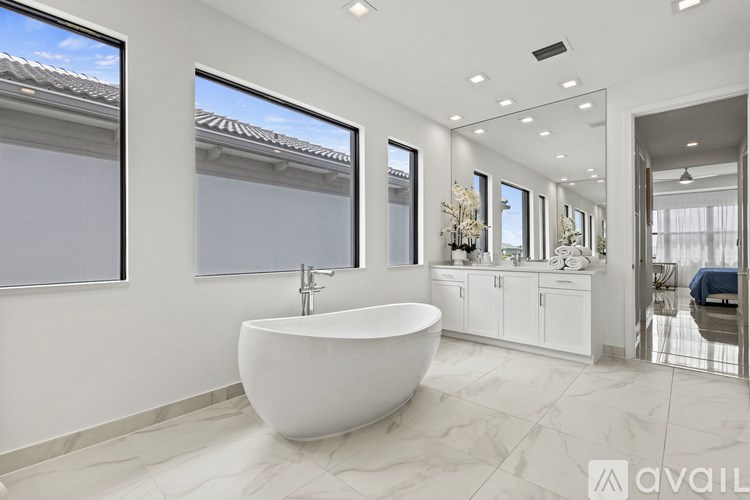 A modern bathroom with a large tub and a view of the sky through the windows.