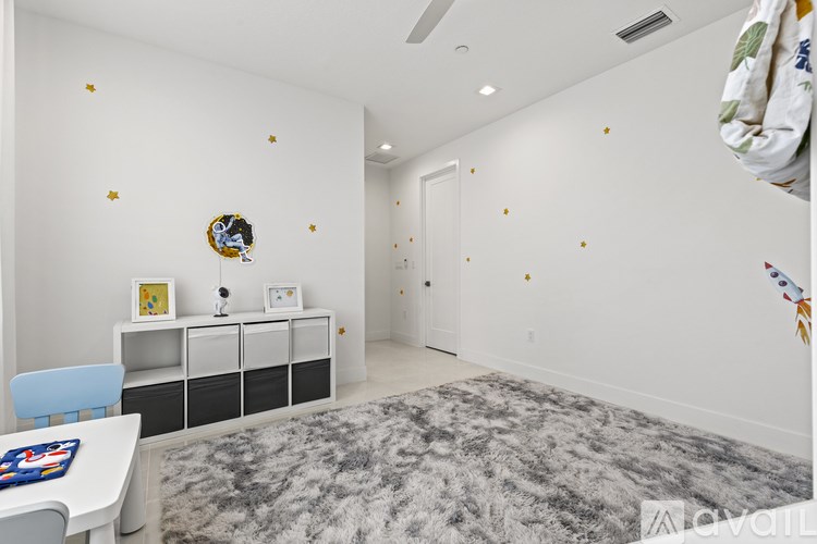 A room with a grey carpet and a white table with a blue chair.