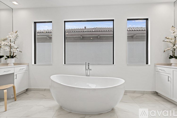 A white bathroom with a large tub and a window.
