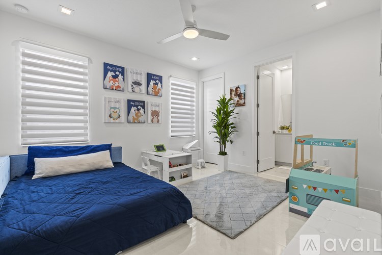 A bedroom with a blue bedspread and a white ceiling fan.