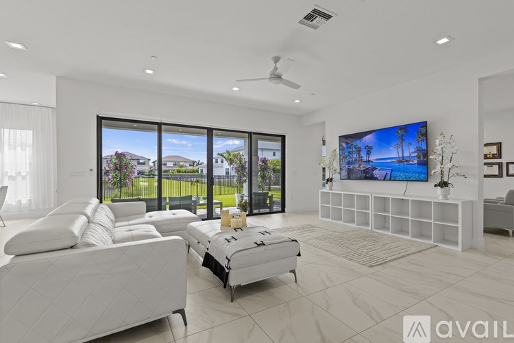 A modern living room with a large white sofa and a television displaying a beach scene.