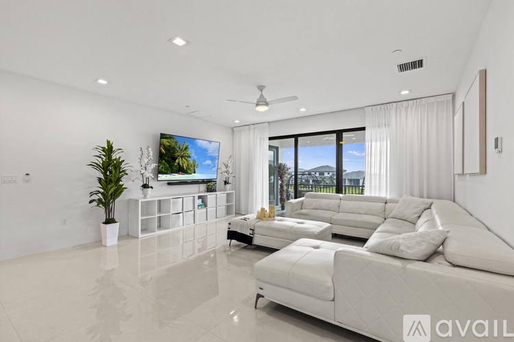 A modern living room with a white sofa and a flat screen TV mounted on the wall.