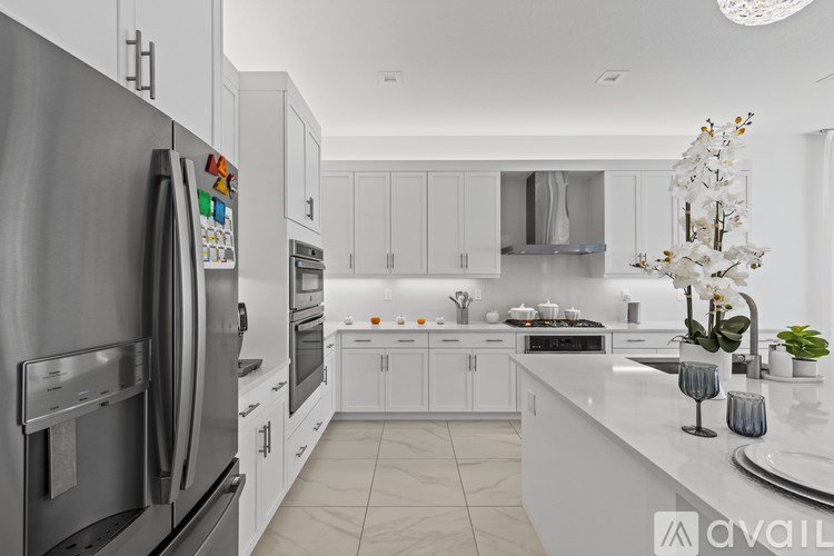 A modern kitchen with a refrigerator on the left and a counter with a vase of flowers on the right.