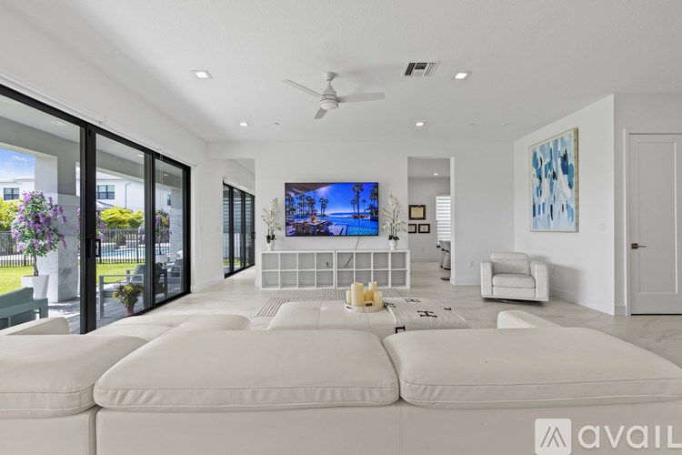 A modern living room with a large white sofa and a flat screen TV mounted on the wall.