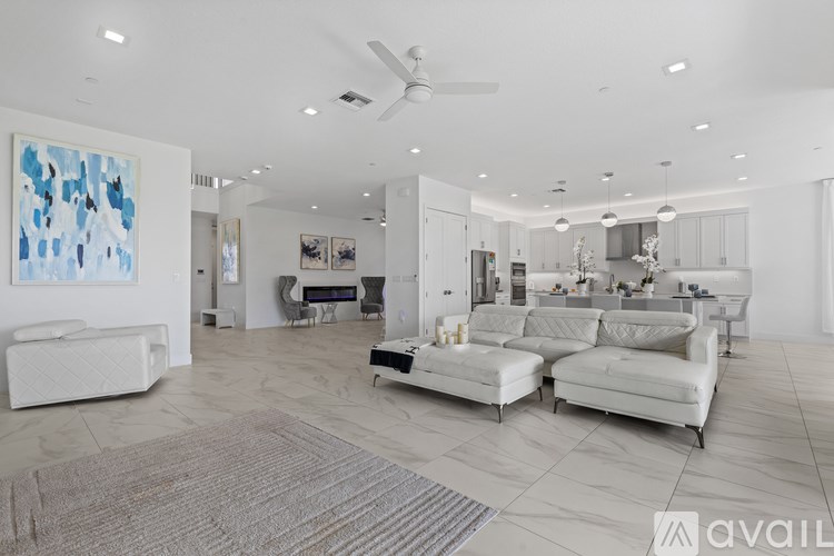 A spacious living room with a grey rug and two white sofas.