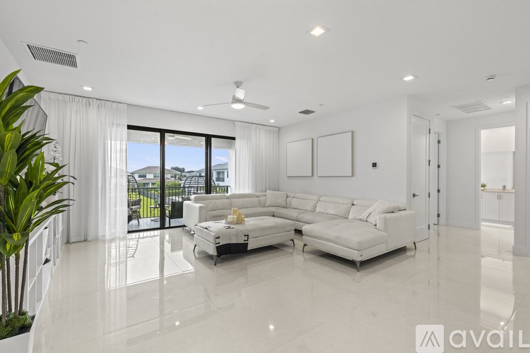 A spacious living room with a large white sofa and a view of the outdoors through the sliding glass doors.