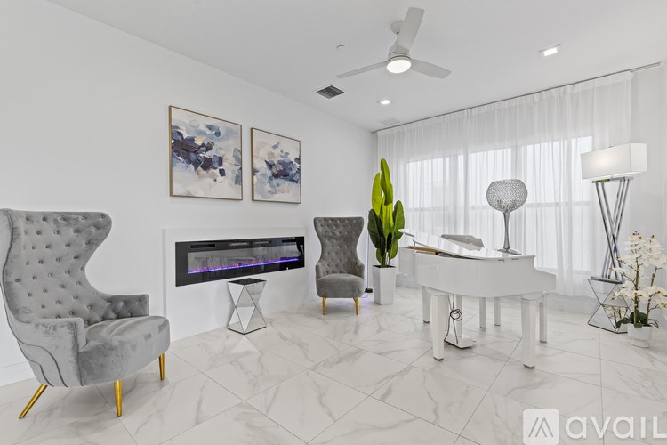A living room with a grey chair, a white piano, and a painting on the wall.
