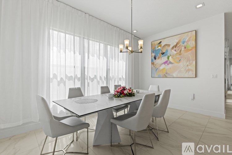 A modern dining room with a white table and chairs.
