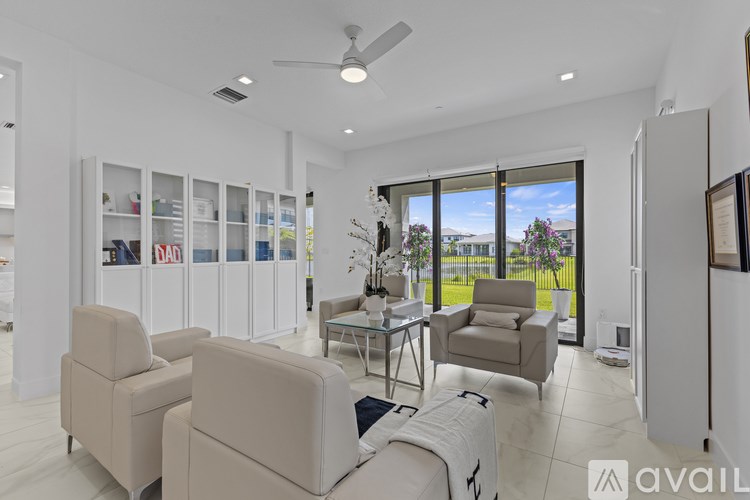 A living room with a white ceiling fan and a glass door leading to a balcony.