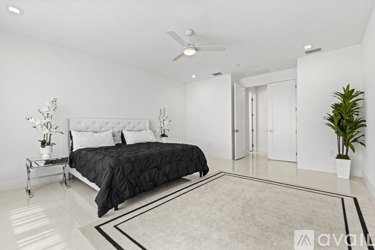 A bedroom with a bed, a bench, and a plant.