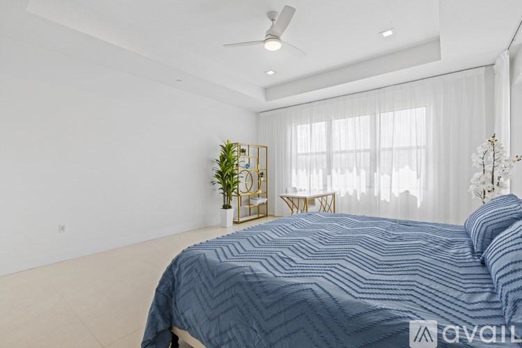 A bedroom with a large bed and a plant on a stand.