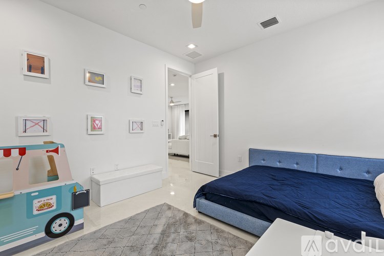 A bedroom with a blue bed and a toy truck on the floor.