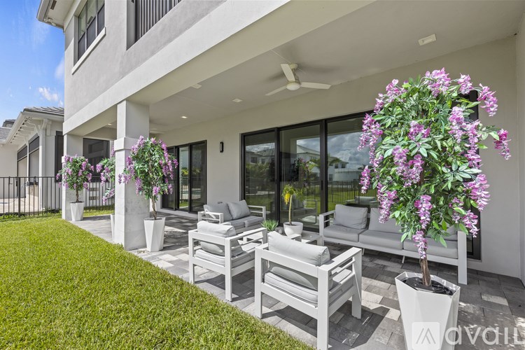 A white patio with a couch, chairs, and a potted plant.