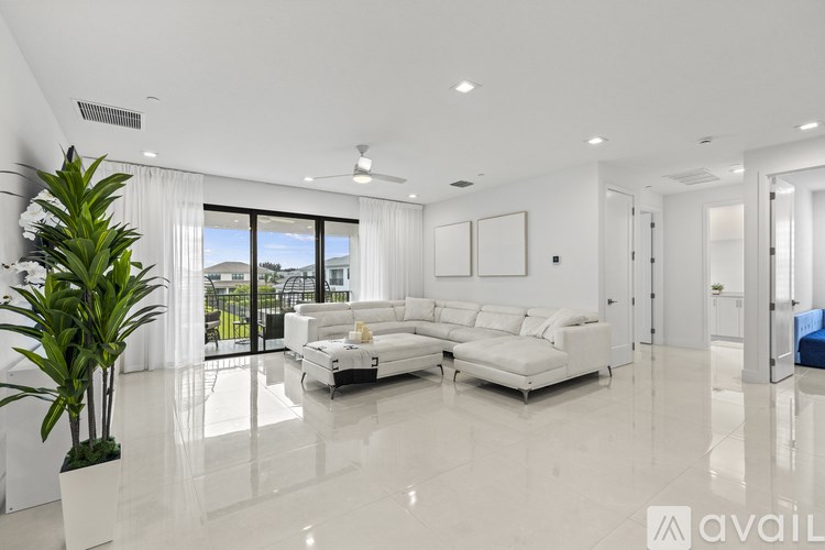 A spacious living room with white furniture and a large window.