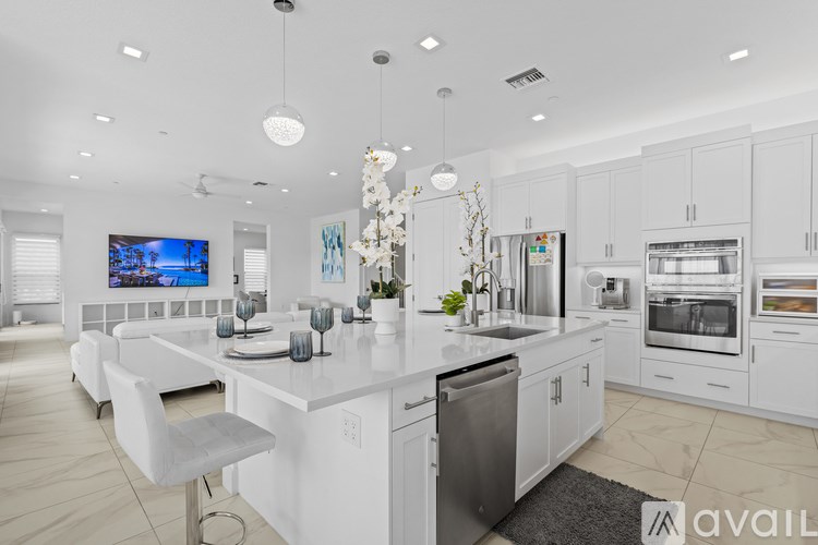 A modern kitchen with a long white island and stainless steel appliances.