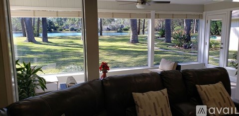 A living room with a couch and a view of a pool and trees outside.