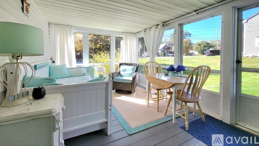 A sunny day in a room with a white bench, a table with chairs, and a window.
