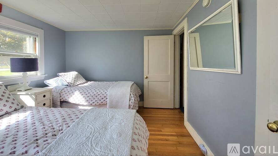 A bedroom with two beds and a mirror on the wall.