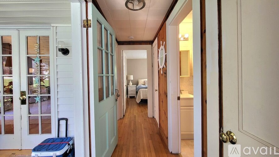 A hallway with a door on the left and a bedroom on the right.
