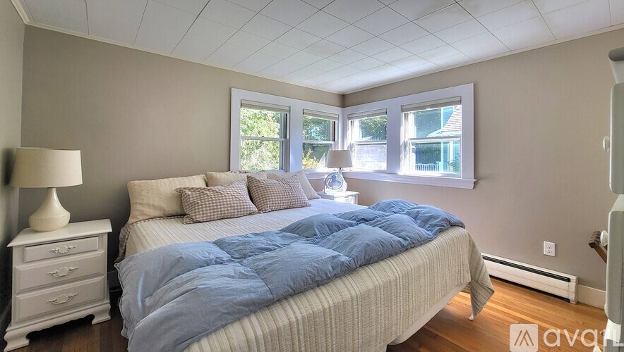 A bedroom with a bed, nightstand, and window.