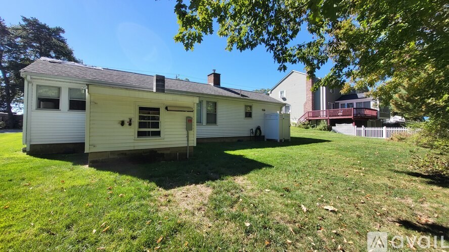 A white house with a red roof and a tree in front.