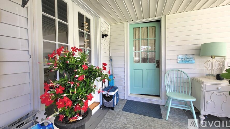 A white house with a blue door and a chair.