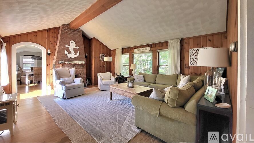 A living room with a couch, chairs, and a rug.