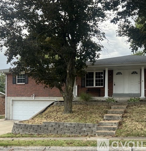 A house with a white door and a tree in front.