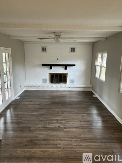 A spacious room with wooden floors and a fireplace.