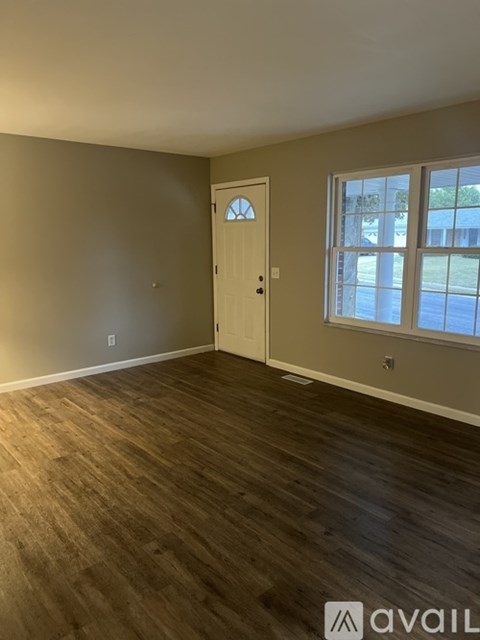 A room with three windows and a white door.