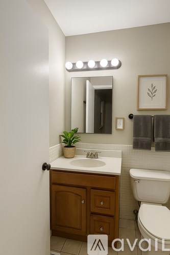 A bathroom with a white sink and a mirror with lights above it.