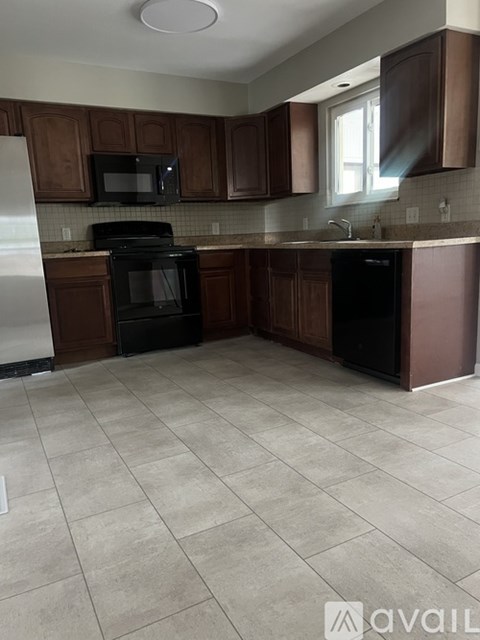 A kitchen with brown cabinets and black appliances.