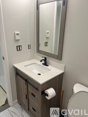 A bathroom with a sink, mirror, and toilet paper.