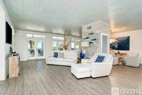 A living room with white furniture and a wooden floor.
