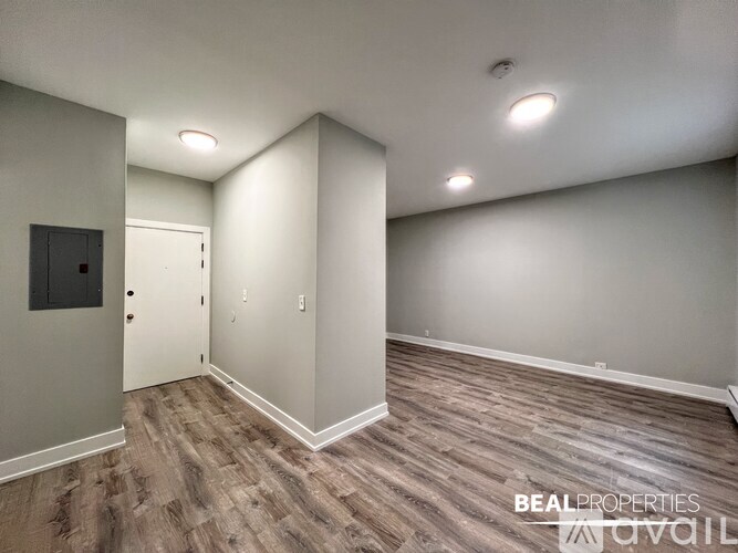 A room with wood flooring and a door on the left side.